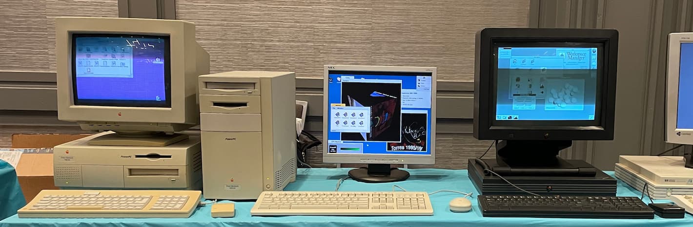 A table with a Power Macintosh 7500 running Copland, an 8500 running BeOS, and a NeXTstation running NeXTSTEP