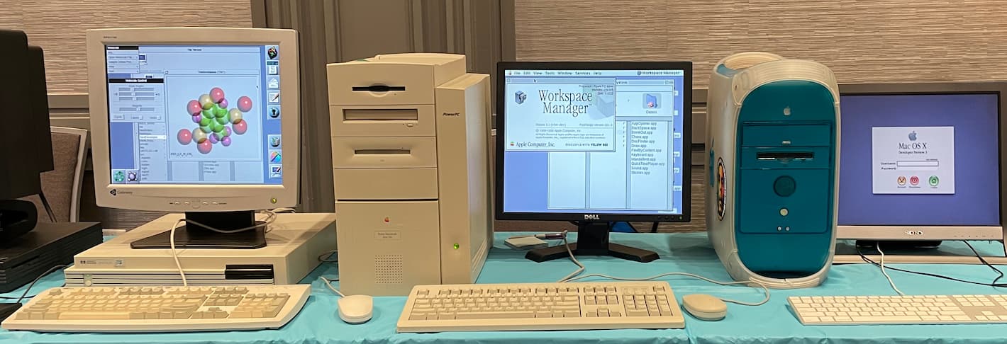 A table with an HP 712 running NeXTSTEP, a Power Macintosh 9600 running Rhapsody, and a Power Macintosh G3 Blue-and-White running a Mac OS X Developer Preview